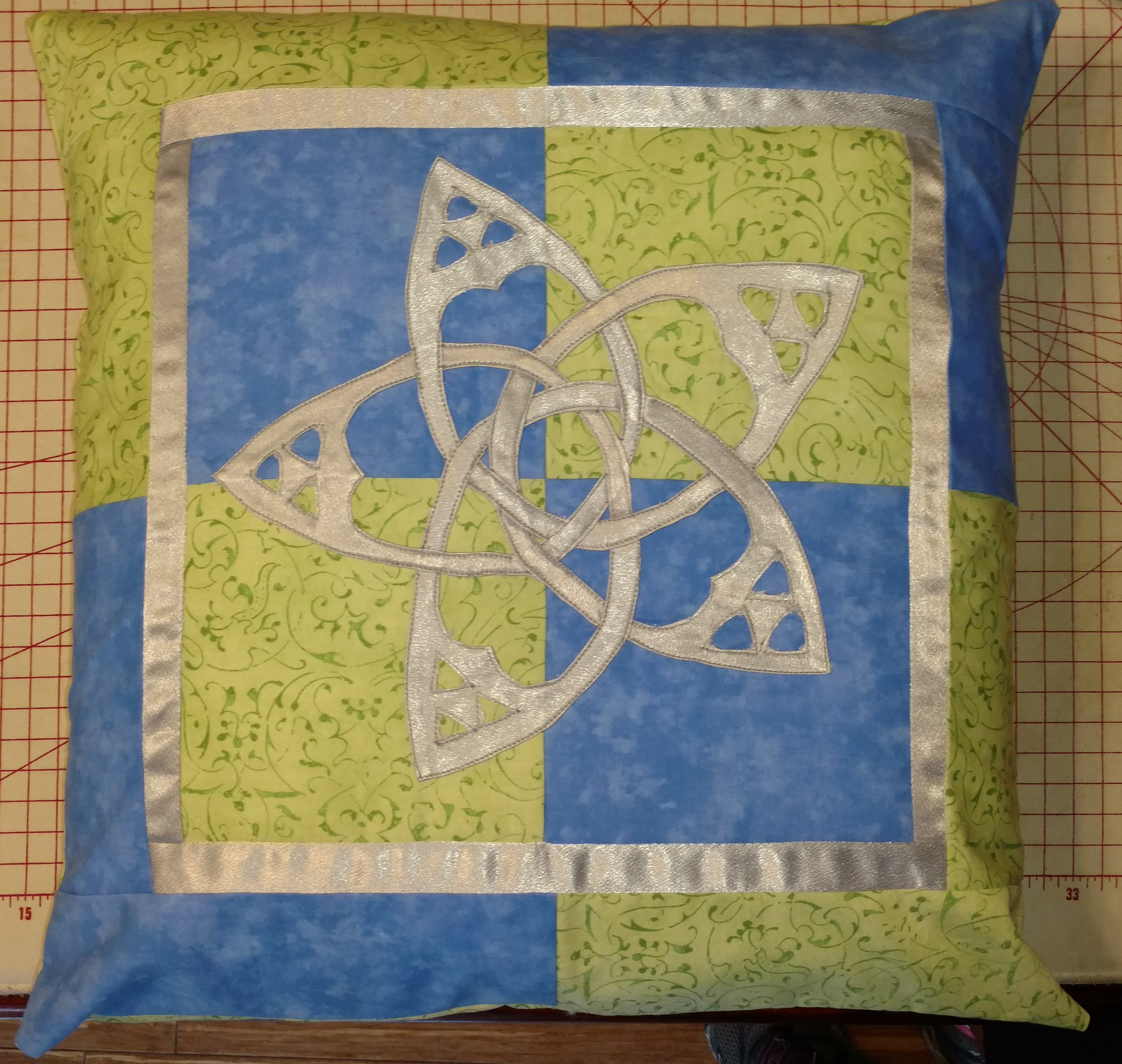 Blue and green pillow with an appliqued Celtic knot