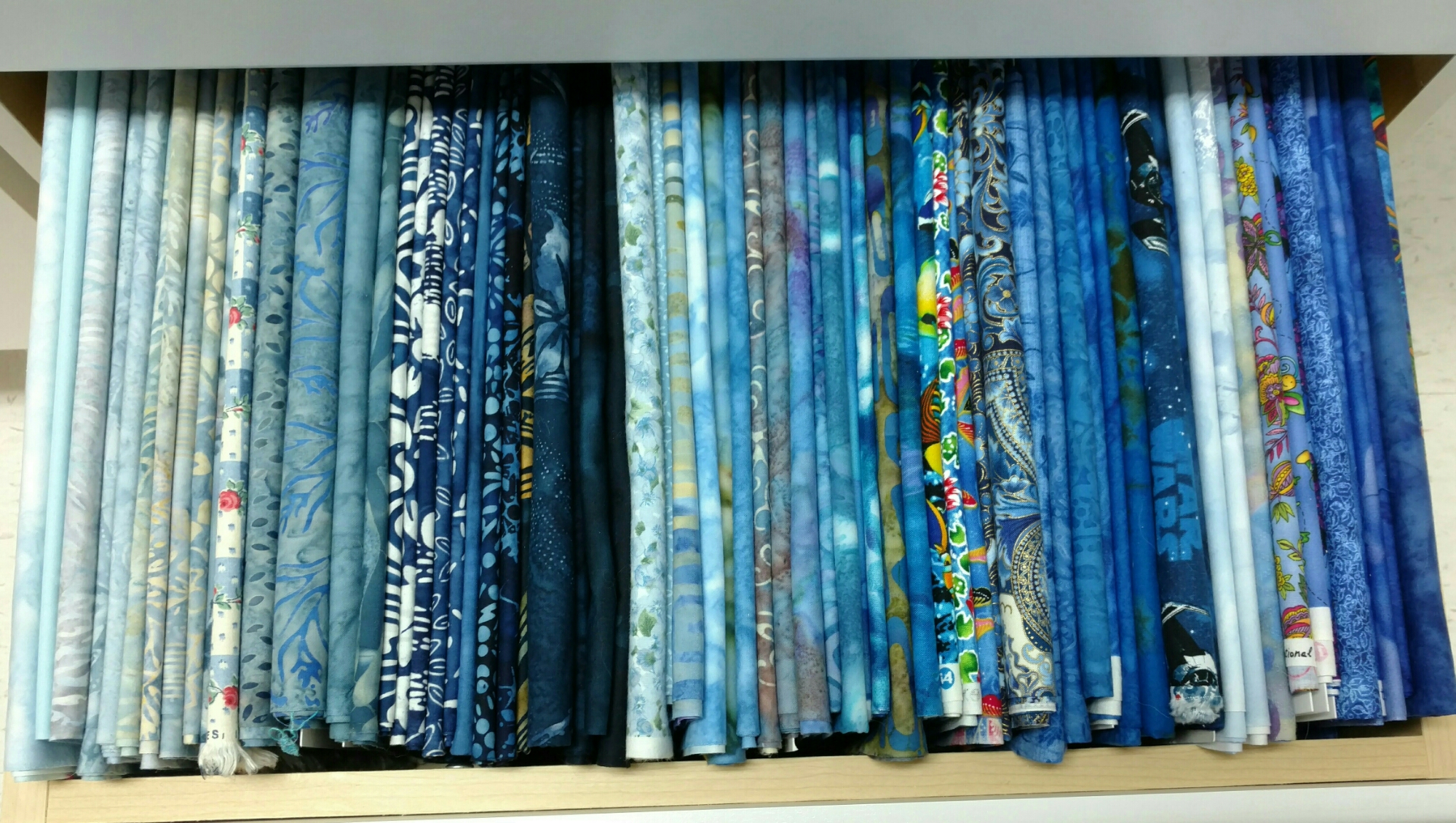 Drawer of folded blue fabrics organized like files