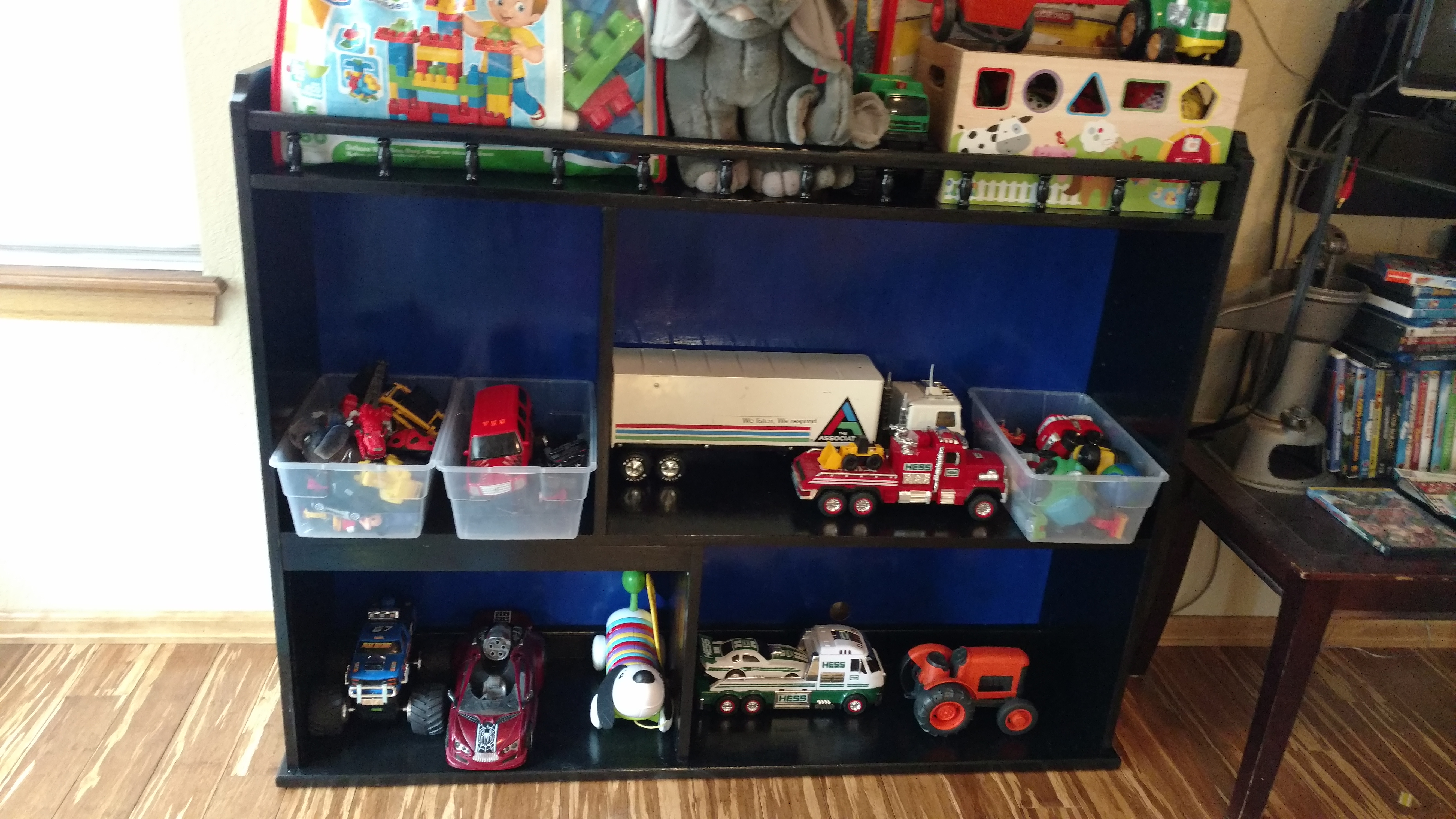 Black toy shelf with bins of toy trucks and games