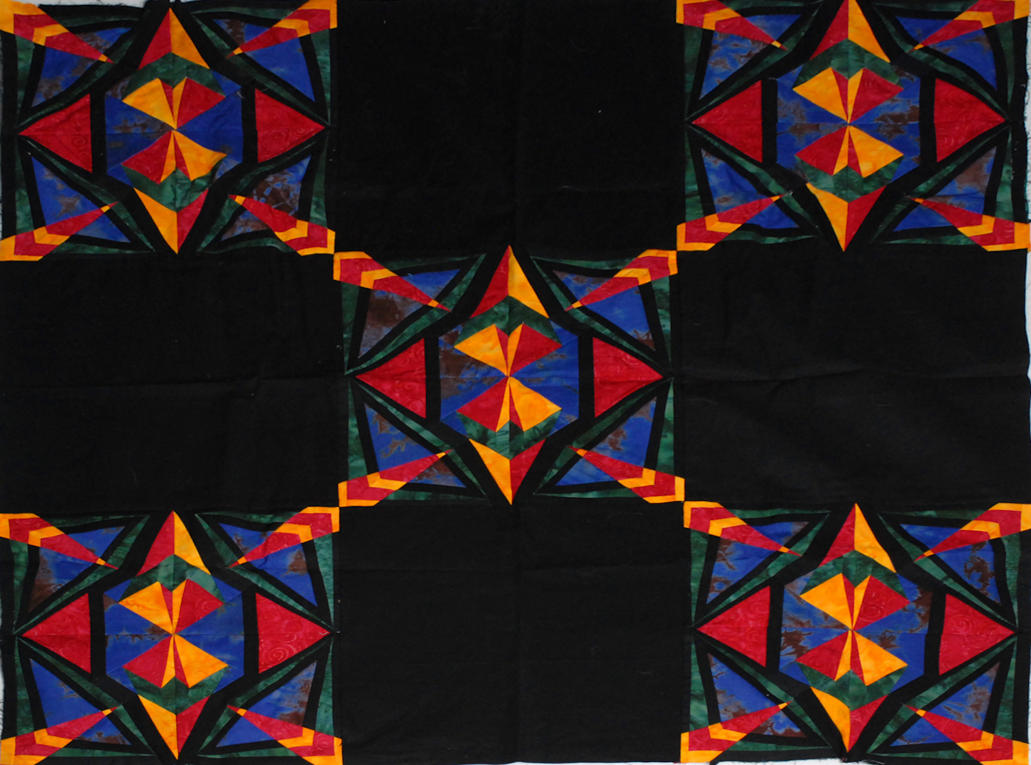 Bright star quilt blocks in red, yellow and blue on black fabric