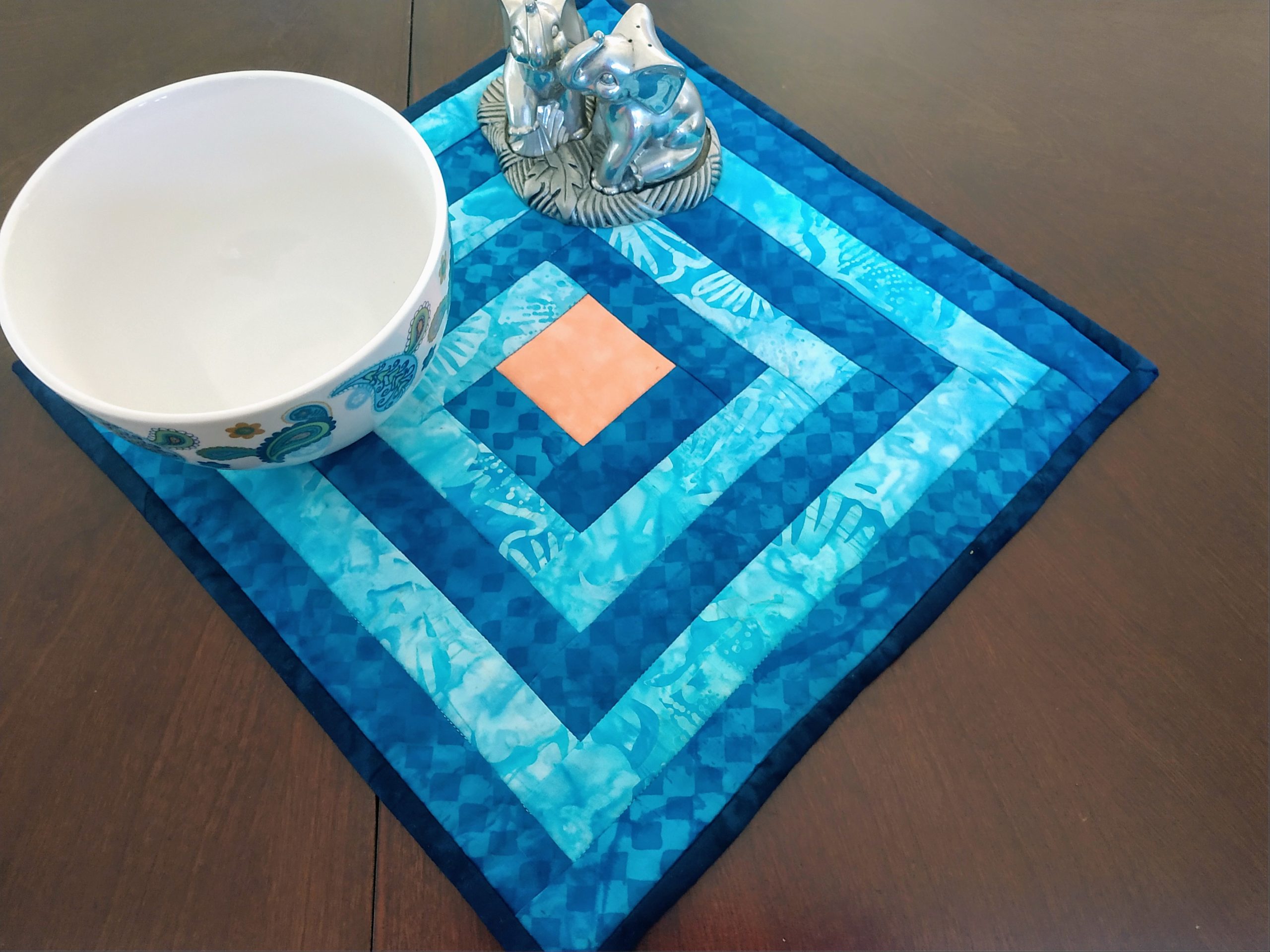 Handmade blue batik Around the World potholder on a table with a bowl