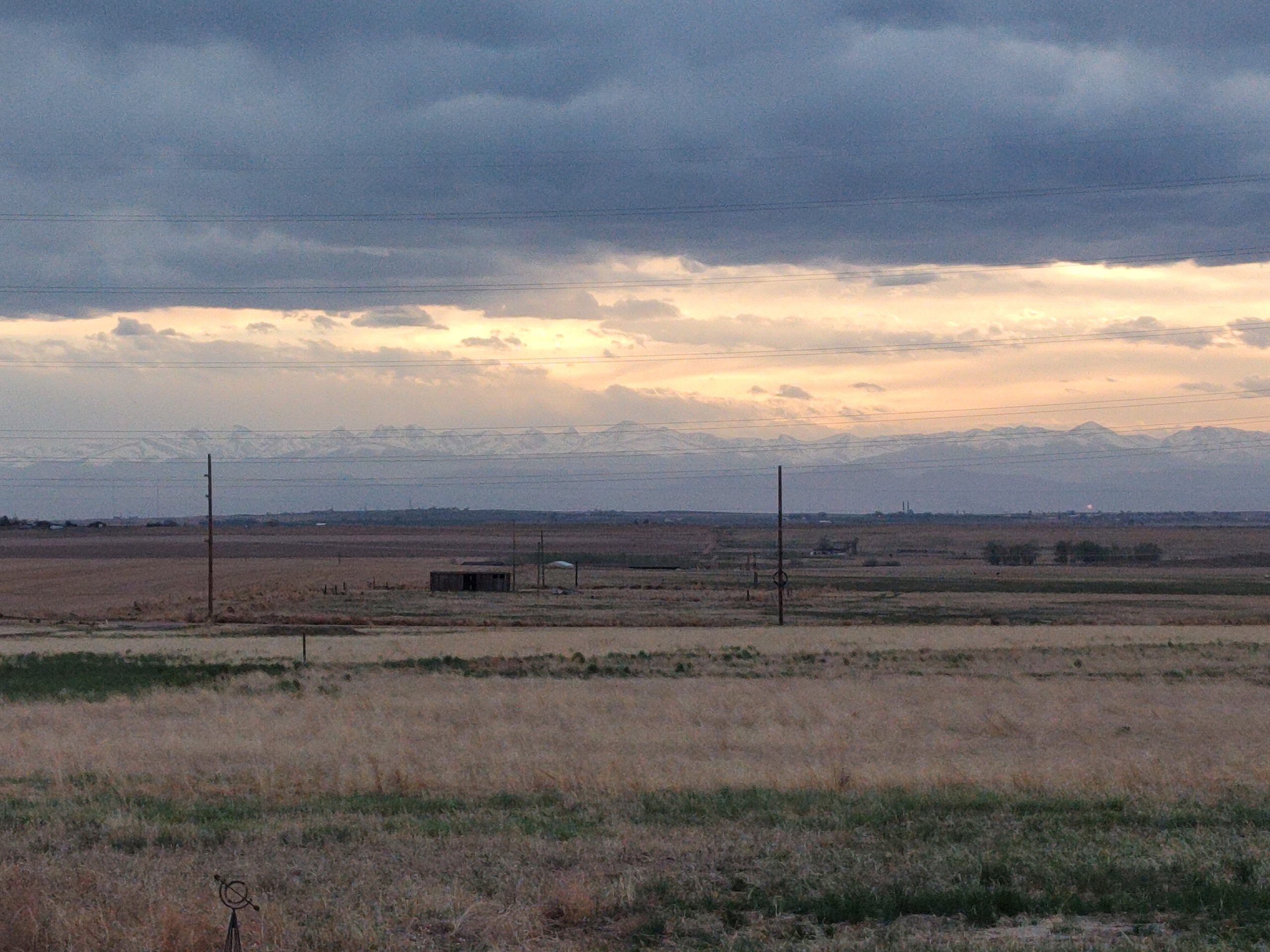 Cloudy sunset over open prairie with power lines